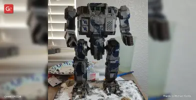 A detailed 3D-printed MWO Highlander mech model, painted and displayed on a textured base.