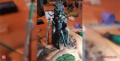 A 3D printed figure of a woman with a helmet and cape sitting on a throne, surrounded by crafting tools.