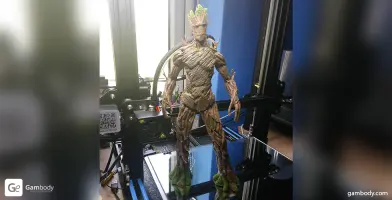 3D-printed model of a tree-like humanoid character with green accents on a 3D printer bed.