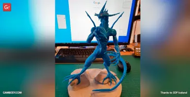 A blue 3D-printed model of Bahamut from Final Fantasy, with dragon-like features, on a desk.