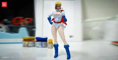 A 3D-printed figure of a superheroine in a white suit with blue gloves and boots, standing confidently.