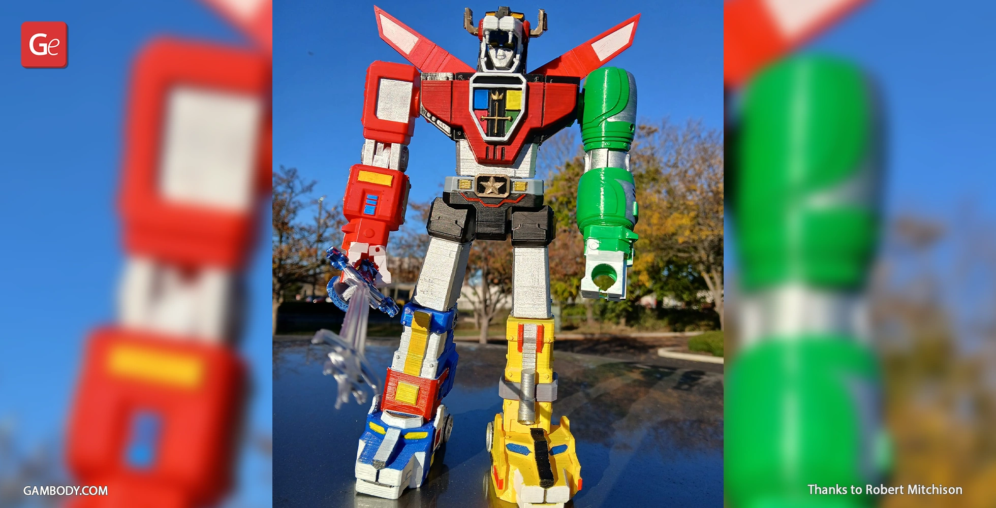 A colorful 3D-printed figure of a robot with distinct red, green, blue, and yellow parts stands outdoors.