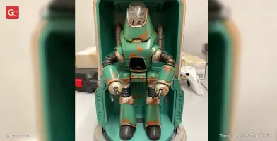A weathered, teal Protectron robot model from Fallout, with rust details, in a display case.