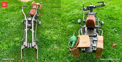 A detailed 3D-printed Mandalorian speeder bike model with a green creature and bags on green grass.