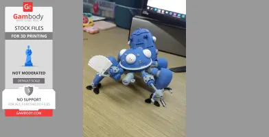 A blue 3D-printed Tachikoma model from 'Ghost in the Shell' on a wooden desk, holding a small fan.