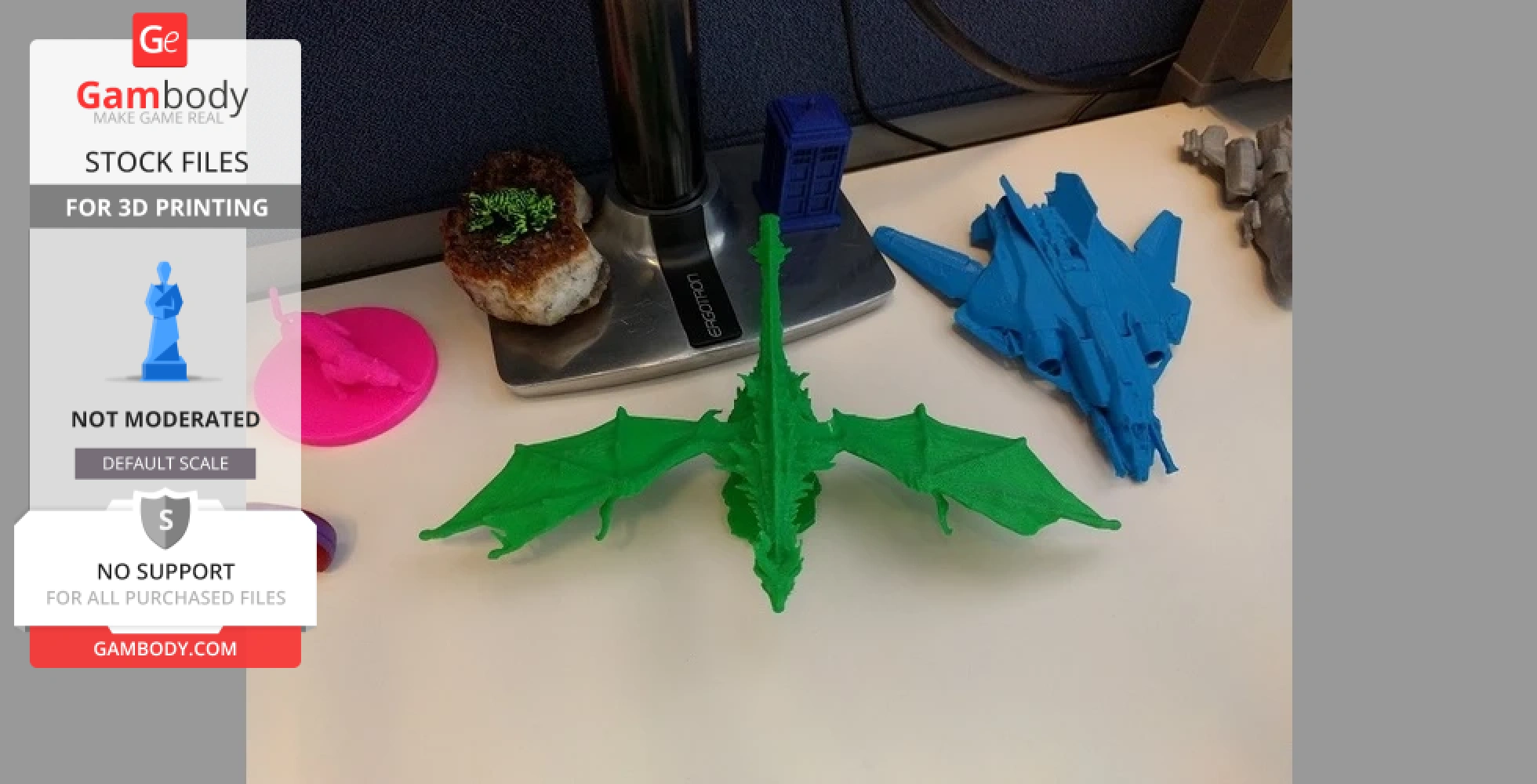 Green 3D printed dragon model on a desk, surrounded by other blue and gray 3D objects.