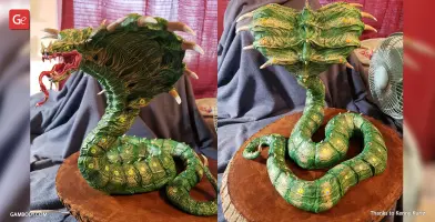 A detailed, green King Cobra model with an open hood and fierce expression on a wooden base.