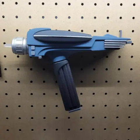 Futuristic gray and black phaser gun model with a sleek design on a wooden surface.