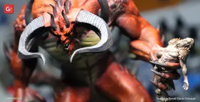 Red demon with large horns holding a smaller warrior figure.