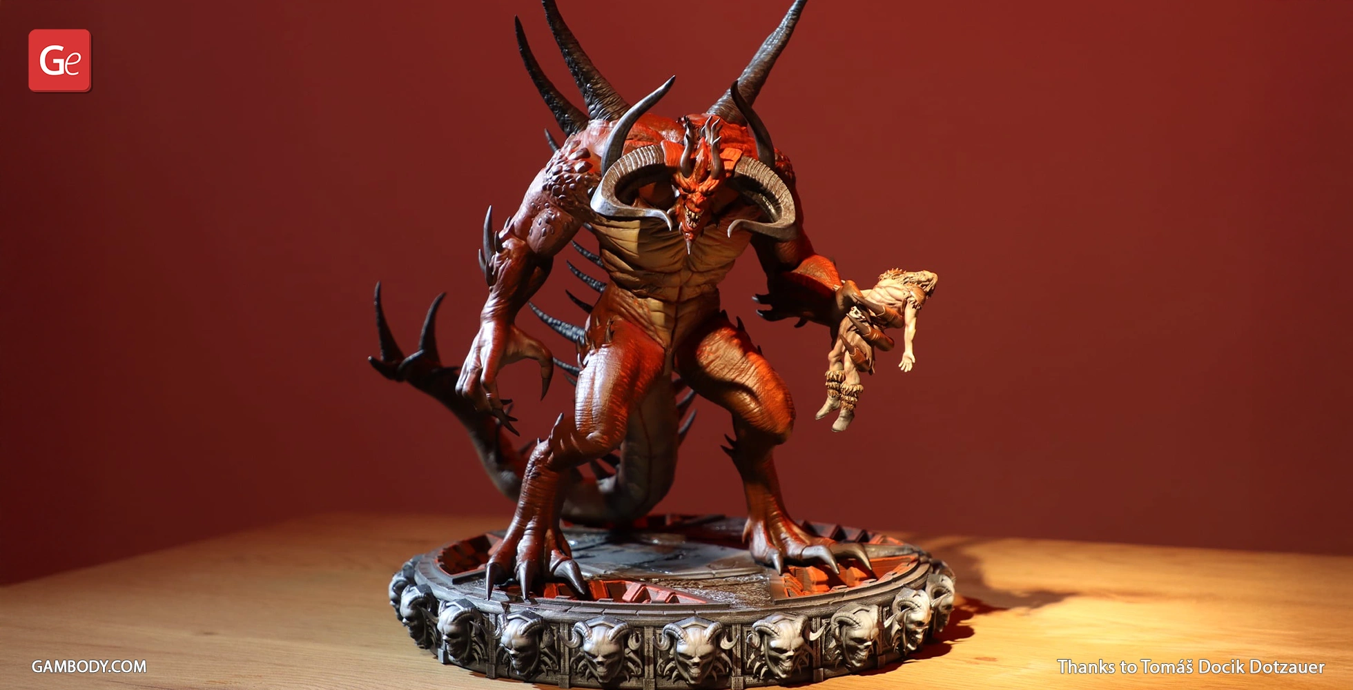 Demon-like figure with horns and spikes, holding a small figure, stands on a detailed circular base.