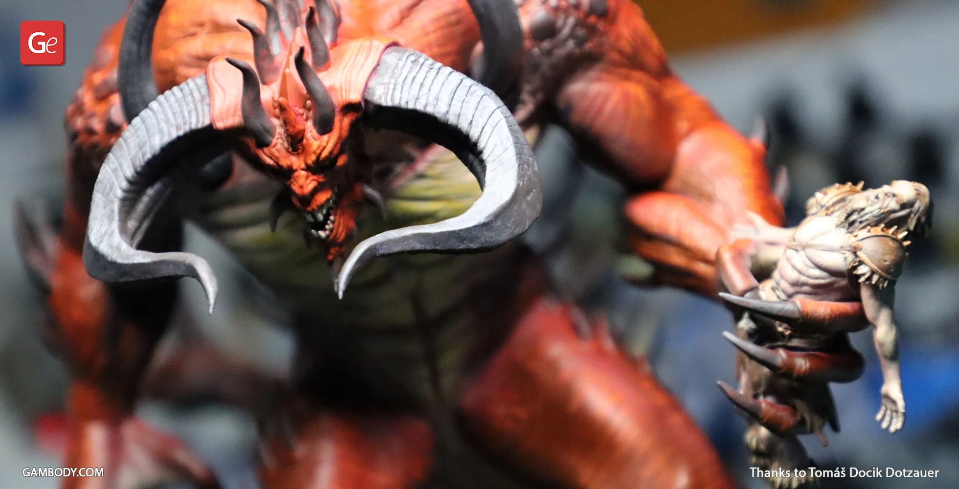 Red demon with large horns holding a smaller warrior figure.