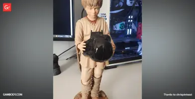 A 3D printed model of a young boy in beige attire holding a black helmet.