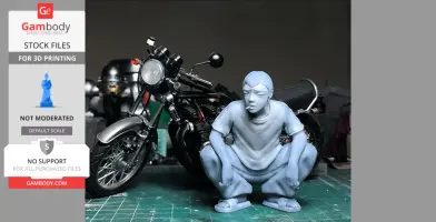 A squatting figurine with a cigarette, next to a detailed motorcycle on a crafting mat.