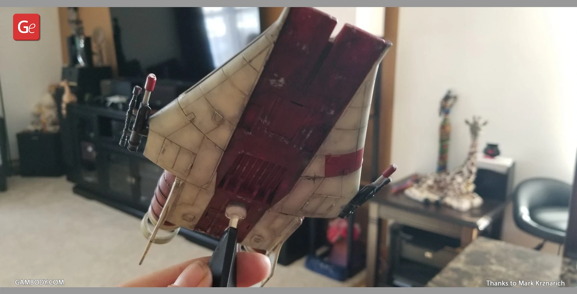 A model of an RZ-1 A-Wing starfighter being held by tweezers.