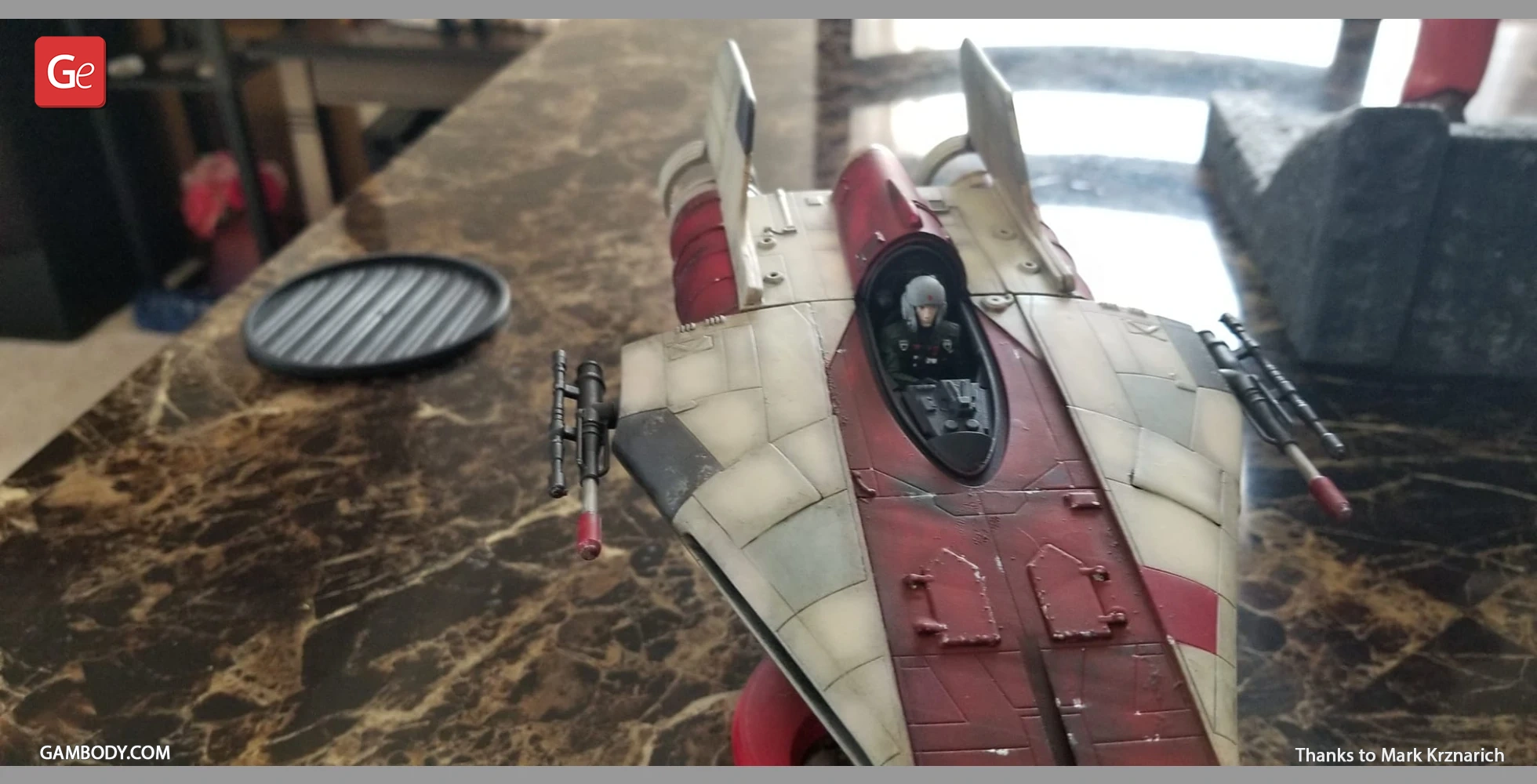 A detailed model of an RZ-1 A-Wing starfighter with a pilot in the cockpit on a marble surface.