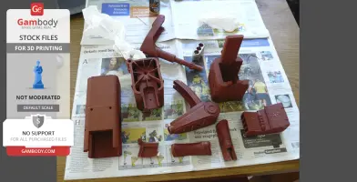 Several 3D-printed parts of a Fallout laser pistol are laid out on newspaper for assembly.