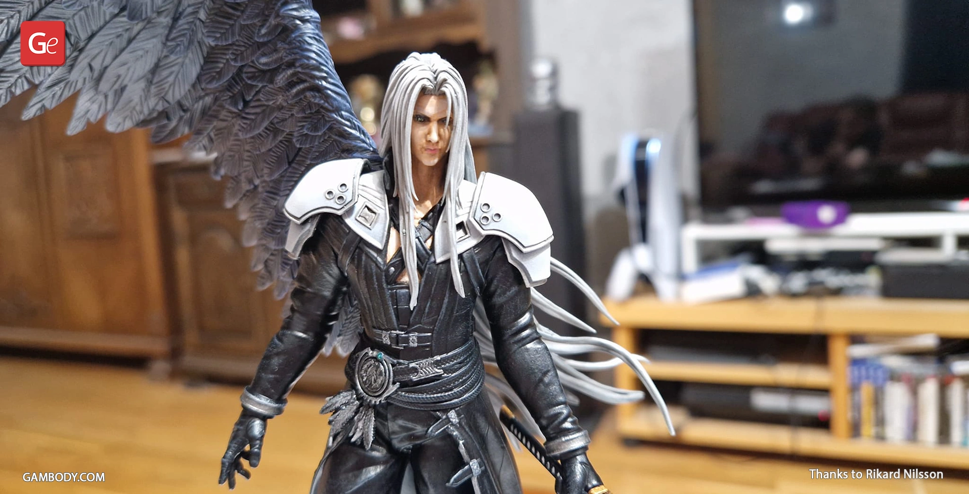 A detailed 3D-printed figure with long hair, dark outfit, and black feathered wings, standing indoors.