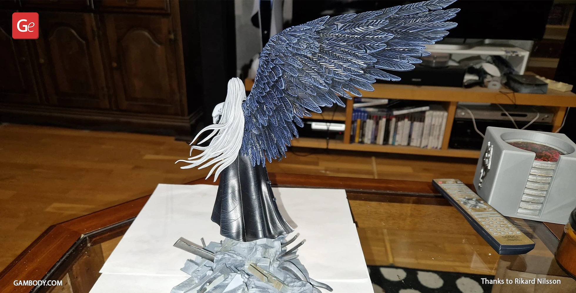A 3D-printed figure with long hair and a large, intricate wing, standing on a rocky base.