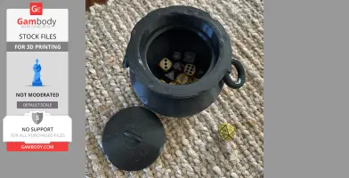A 3D-printed black cauldron with detached lid, containing various dice on a woven surface.