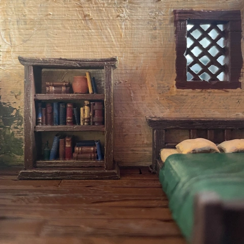 Cozy room diorama with a wooden bookshelf, bed, and lattice window.