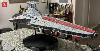 A detailed 3D printed model of a Venator-class Star Destroyer displayed on a stand indoors.