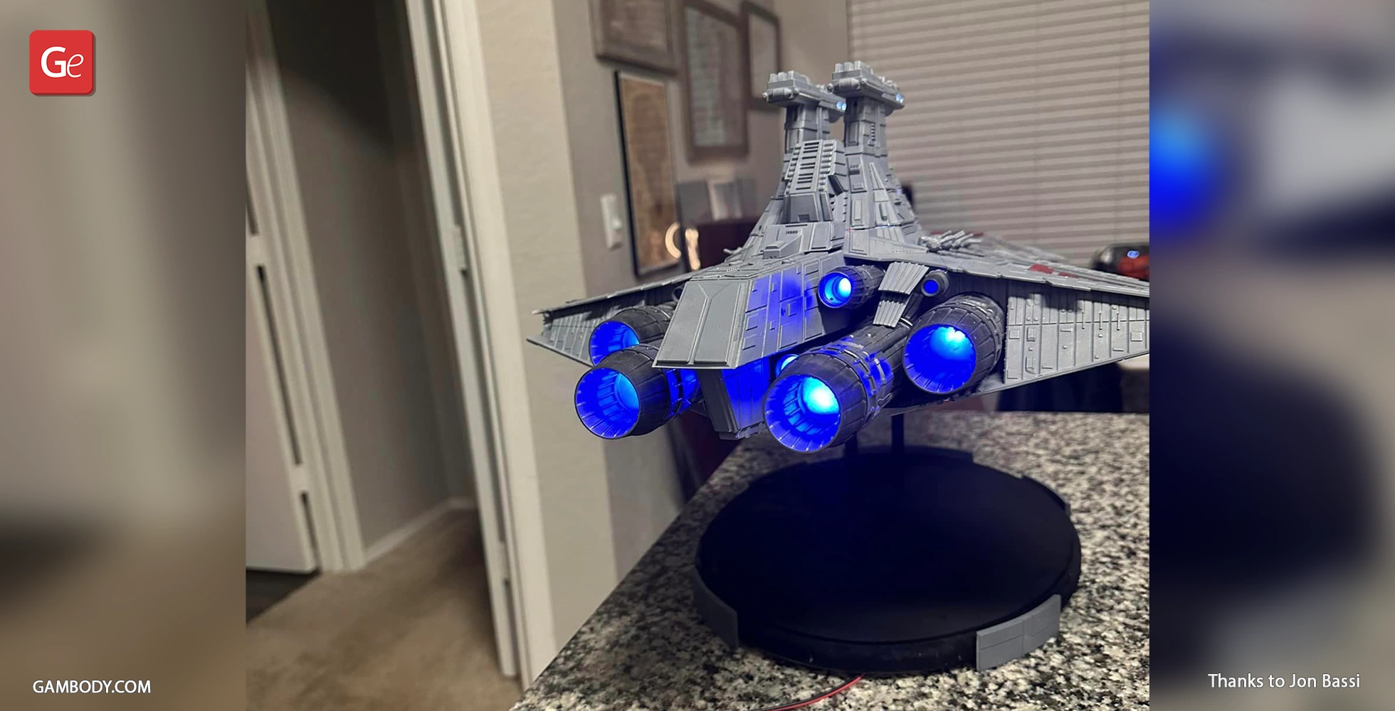 Venator-class Star Destroyer model with illuminated blue thrusters on a display stand.
