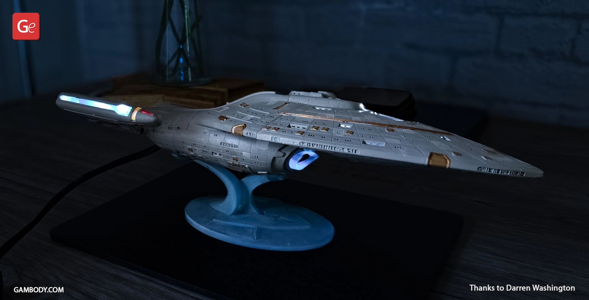 A detailed 3D printed model of the USS Voyager starship on a stand, with illuminated details.
