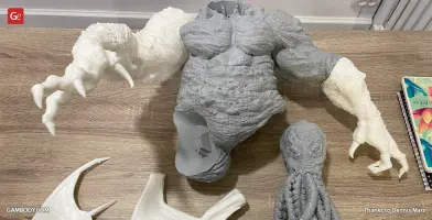 A partially assembled 3D printed Cthulhu model with distinct head, torso, and arms on a table.