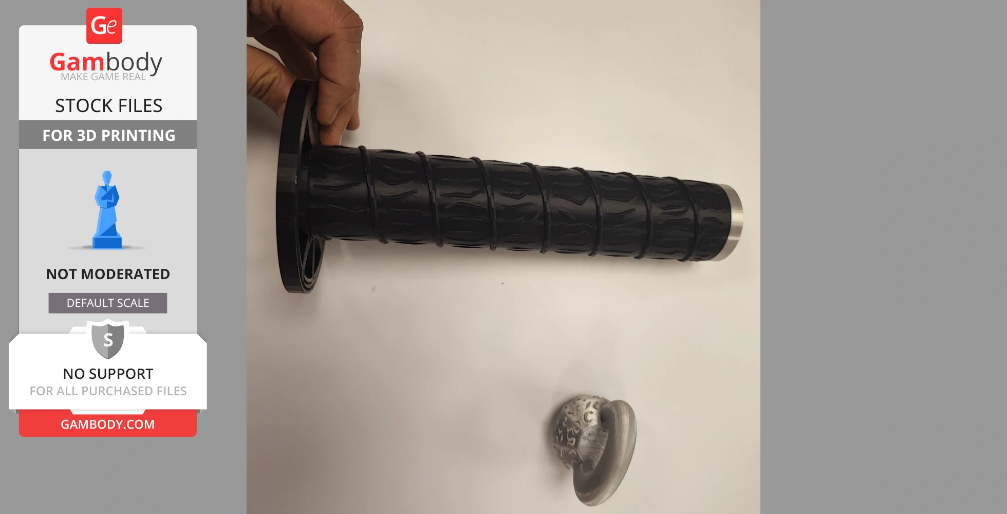 A hand holding a detailed 3D-printed sword handle and a separate circular piece on a white surface.