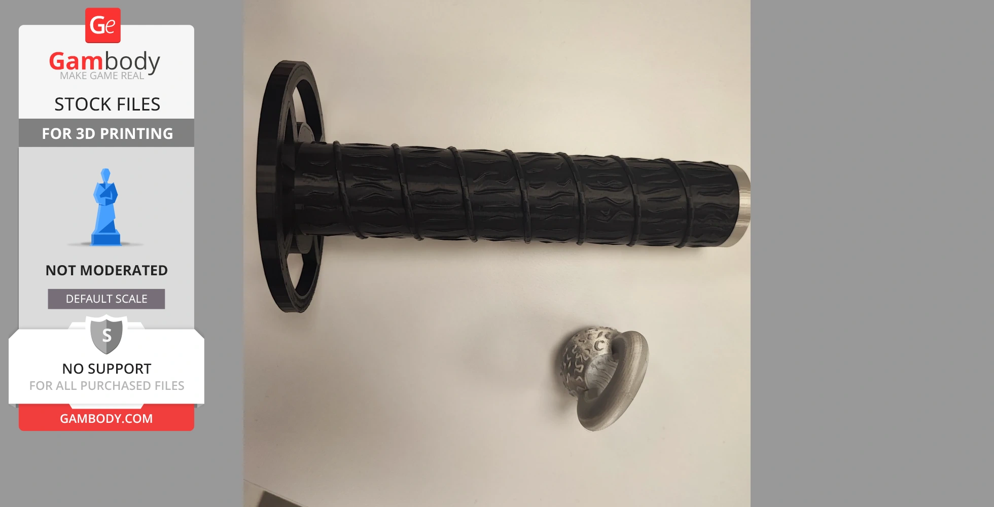 Black textured sword handle and small decorative metallic piece on a white surface.