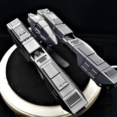 Futuristic spacecraft model with angular structure and cockpit, mounted on a display stand.