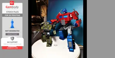 Two 3D-printed robot models, one green and one red-blue, posed on a turntable with a blue backdrop.