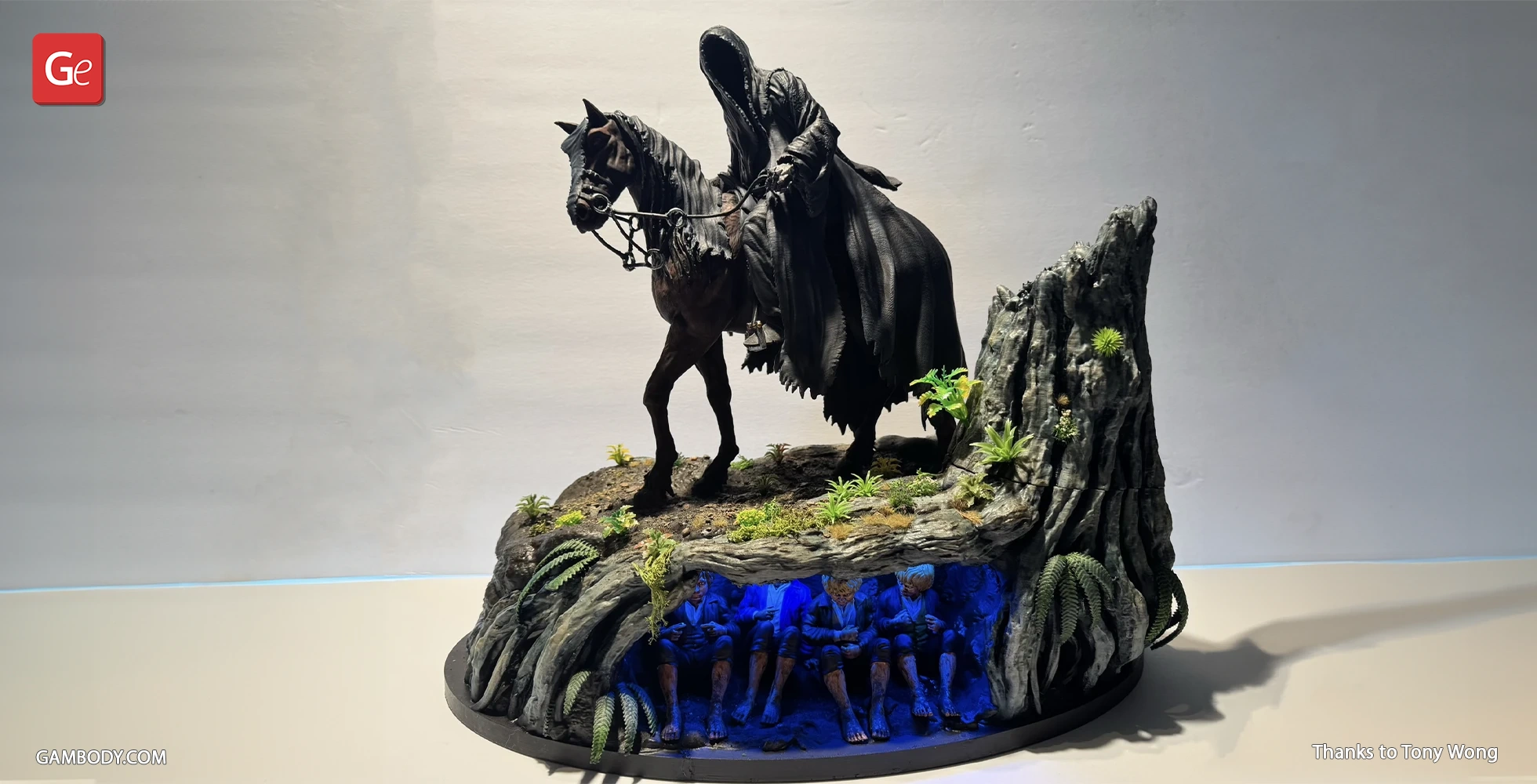 A hooded figure on horseback atop a rocky diorama with hidden, glowing figures underneath.