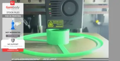 A 3D printer creating a green filament spool on a print bed, with a caution label visible on the printer head.