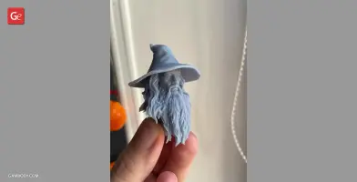 3D-printed bust of a bearded figure in a wide-brimmed hat, held in a hand.