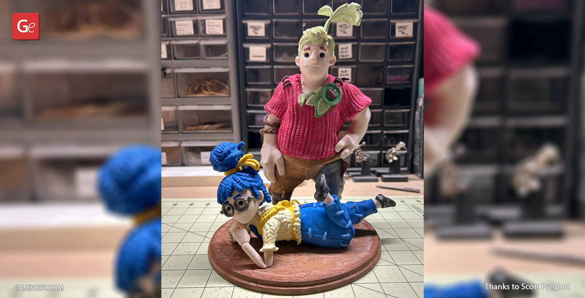 Two stylized figures on a diorama base; one standing, one lying down, with colorful outfits and accessories.