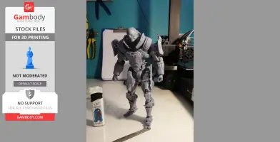A detailed, gray 3D-printed armored figure stands on a desk near a 3D printer and tools.
