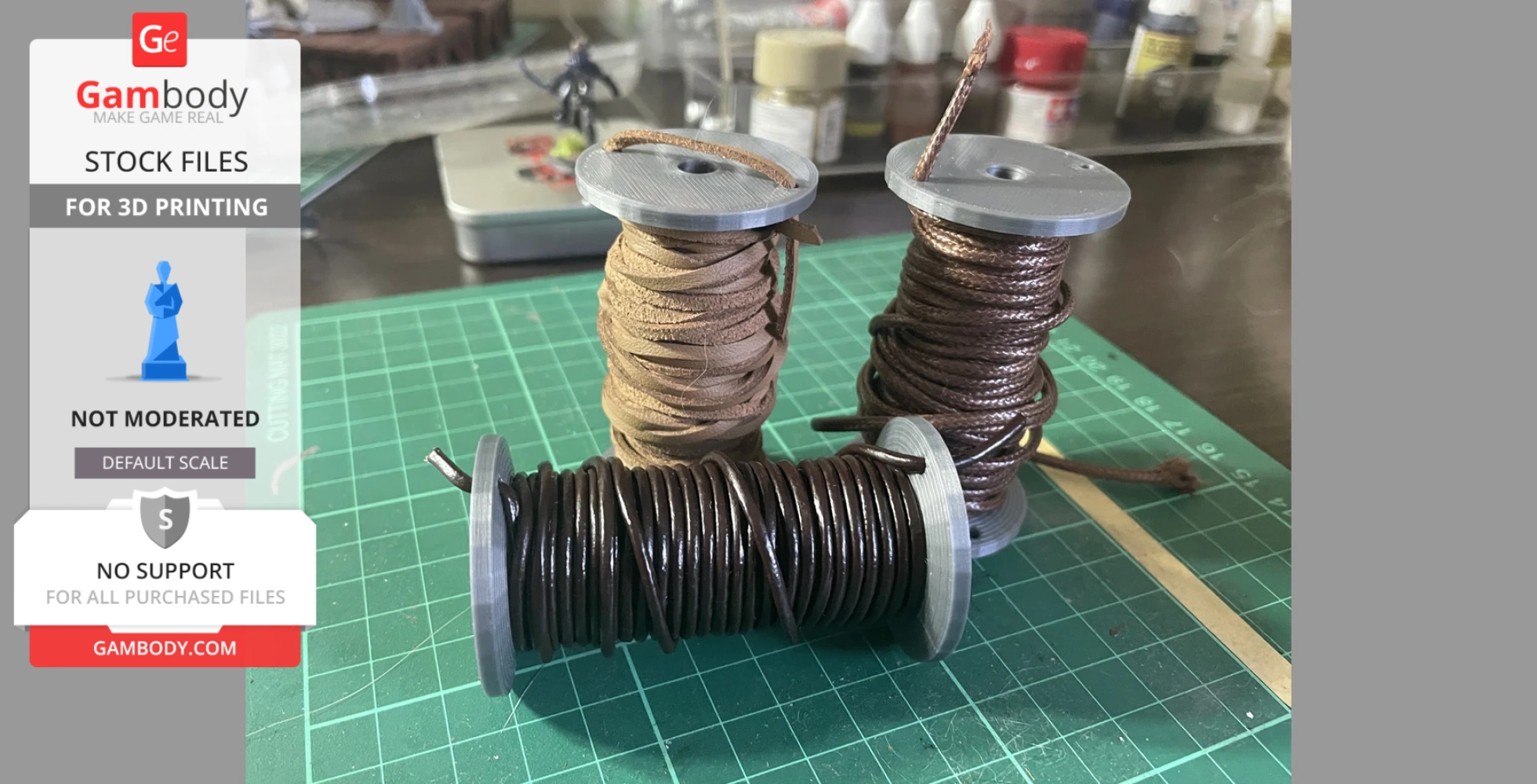 Three spools wrapped with brown and black threads on a green cutting mat.