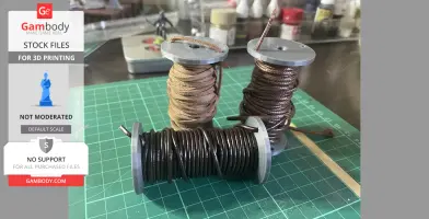 Three spools wrapped with brown and black threads on a green cutting mat.