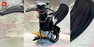 3D model of Toothless, a black dragon with green eyes and wings, sitting on a rocky base.