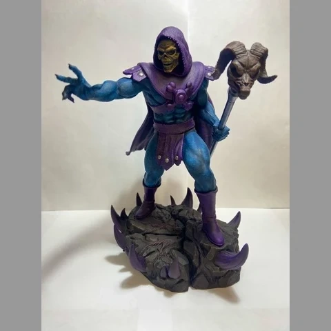 A blue, muscular sorcerer with a skull face and cloak, holding a staff, stands on a rocky base.