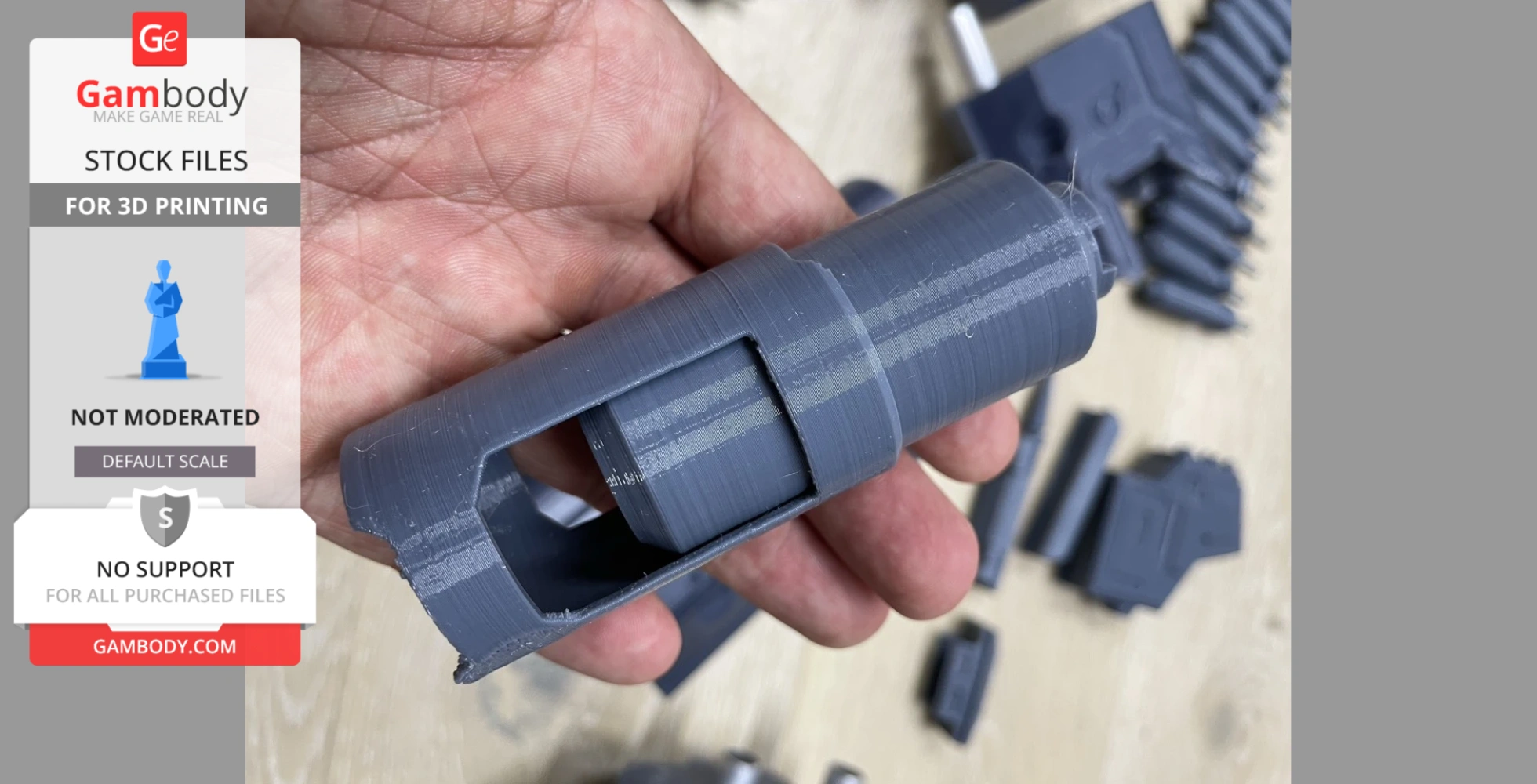 A hand holding a 3D-printed gray part of a District 9 AR replica, with more pieces in the background.