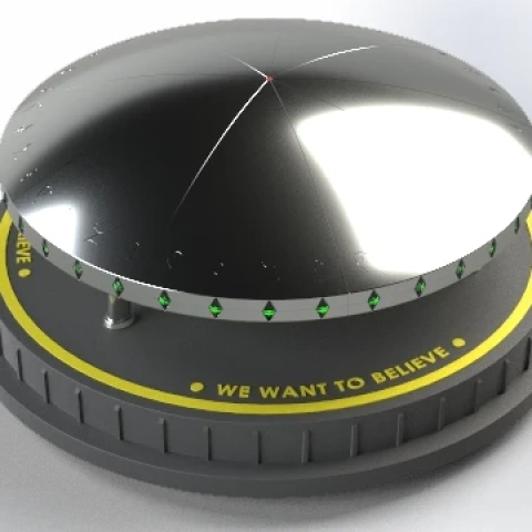 Futuristic silver disc-shaped ship with green lights and 'WE WANT TO BELIEVE' text on base.