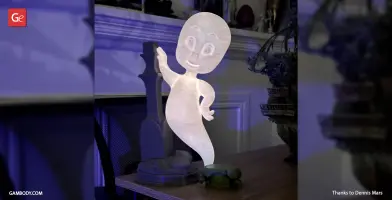 A glowing 3D printed cartoon ghost in a playful flying pose on a tabletop.
