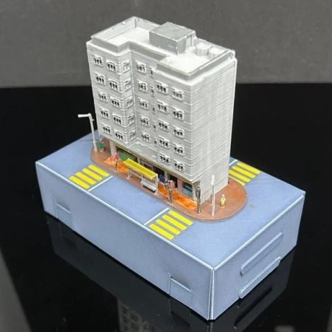 A detailed 3D-printed model of a Hong Kong building on a street base with crosswalks.