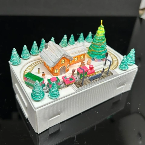 Miniature Christmas train set with snowy village, track, trees, and a train on a rectangular base.