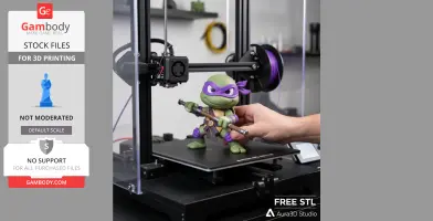 A 3D-printed Donatello figure on a printer bed, being adjusted by a hand.