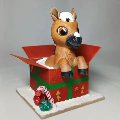 A cute horse figurine peeking out of a festive gift box with candy canes and ornaments.