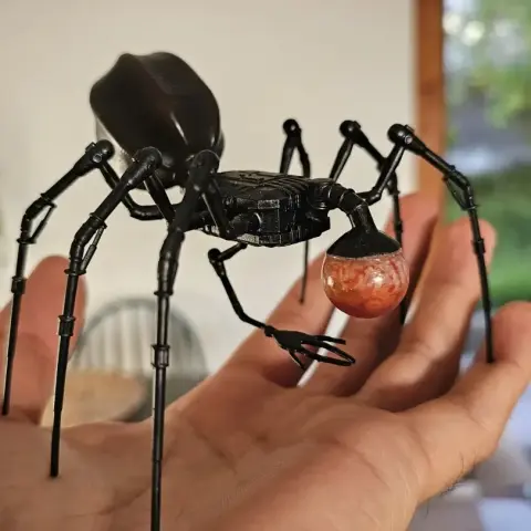 A detailed 3D-printed B'omarr Monk model with spider-like body on a person's hand.