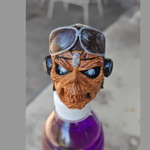 A detailed skull with goggles and headphones mounted atop a purple-capped bottle.